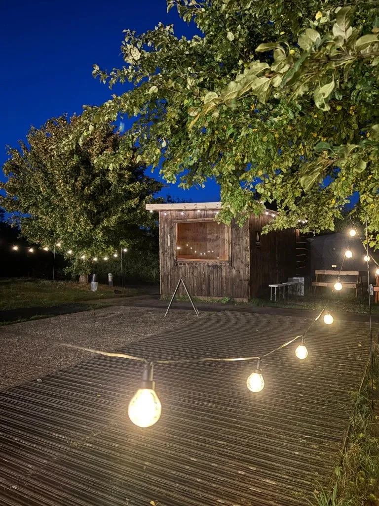 Festoon lights along the decking in front of the sauna at night